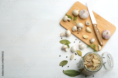 Fototapeta Naklejka Na Ścianę i Meble -  Glass jar of pickled mushrooms on white wooden table, flat lay. Space for text