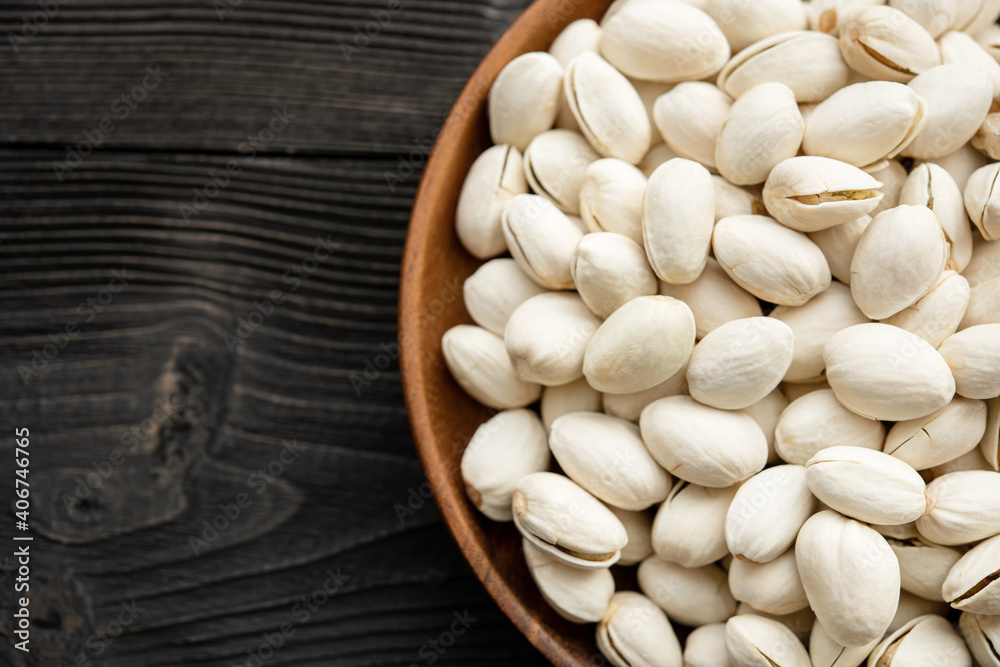 Bowl with pistachios on a wooden table. (selective focus; close-up shot) Bowl with pistachios on a wooden table. (selective focus; close-up shot)