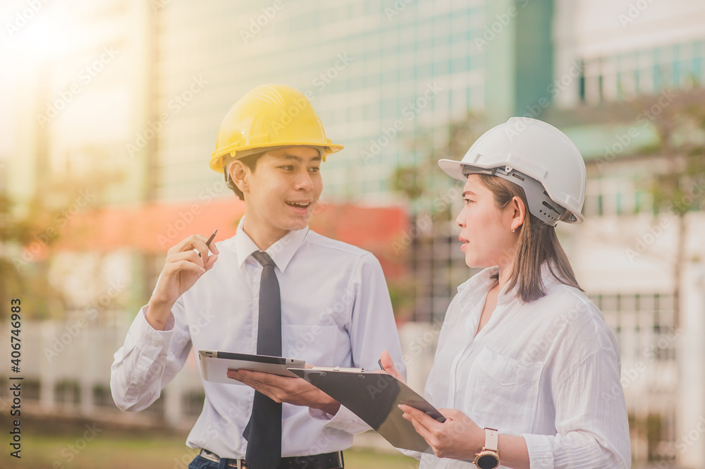 Two worker tablet talking business project property real estate development , Asian man Asian women are engineer professional standing outdoor Two worker tablet talking business project property real estate development , Asian man Asian women are engineer professional standing outdoor