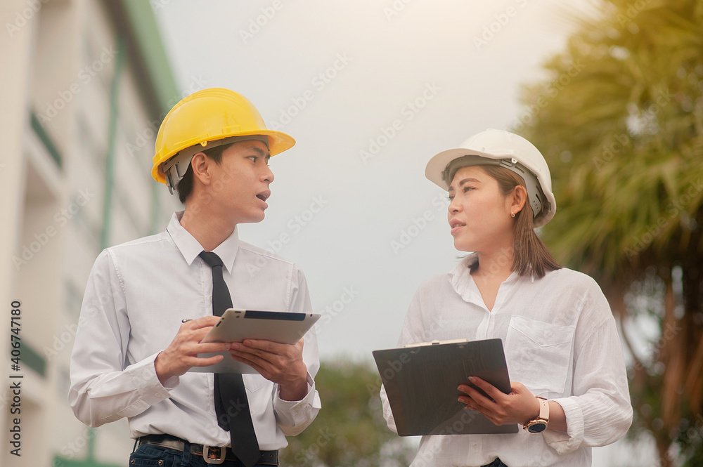 Two worker tablet talking business project property real estate development , Asian man Asian women are engineer professional standing outdoor Two worker tablet talking business project property real estate development , Asian man Asian women are engineer professional standing outdoor