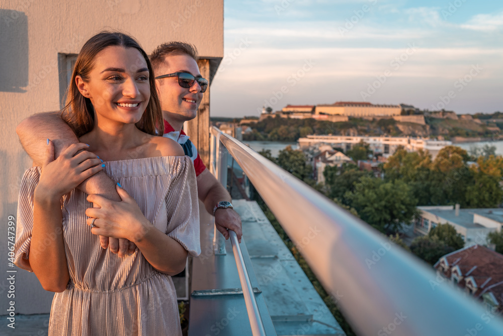 Beautiful young couple just engaged on rooftop of building with beautiful view. Boyfriend and girlfriend on rooftop hugging. Love concept 