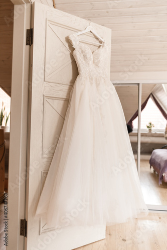 Ivory lace wedding long dress hanging on a wooden hanger