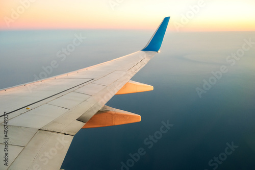 View from airplane on the aircraft white wing flying over ocean landscape in sunny morning. Air travel and transportation concept.