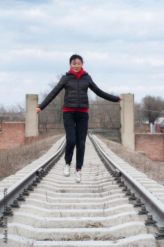 chinese woman jumping on railroad tracks