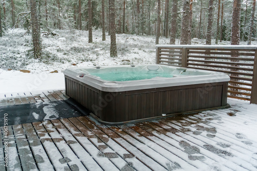Modern outdoor hot tub on a wooden deck in the cold winter day, Finland.