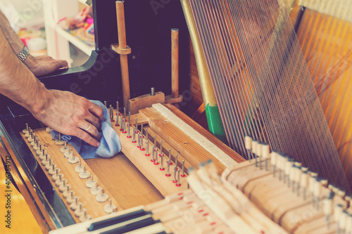 Setting up an old piano. The master repairs an old piano. Deep cleaning the piano. Hands of professional worker repairing and tuning an old piano. toned