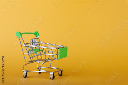 Empty supermarket shopping grocery cart on colored background