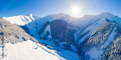 sunny winter day in the snow-covered tyrolean mountains with a small mountain village and forest near bichlbach with sunbeams
