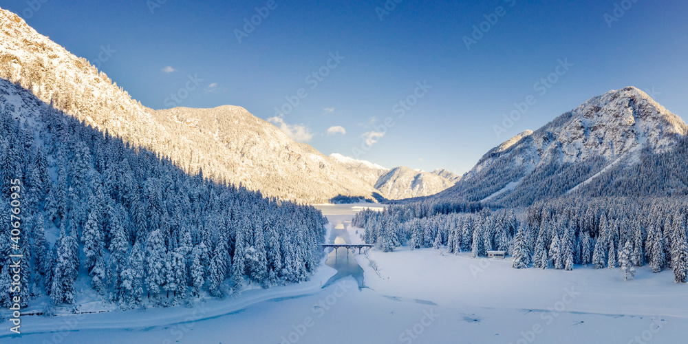 Canal bridge between lake plansee and heiterwangersee in snowy winter and frozen water in the middle of tyrol's mountains