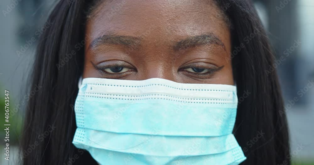 Close up portrait of gorgeous dark skinned woman wearing protective mask against COVID virus. Afrrican american female with medical mask in public post covid space. Safe travel after pandemic concept Close up portrait of gorgeous dark skinned woman wearing protective mask against COVID virus. Afrrican american female with medical mask in public post covid space. Safe travel after pandemic concept