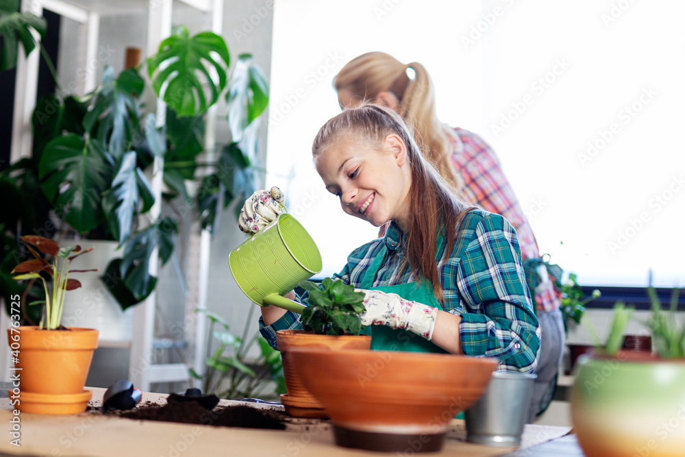 Mum and her daughter at home taking care for flowers and having fun time together Mum and her daughter at home taking care for flowers and having fun time together