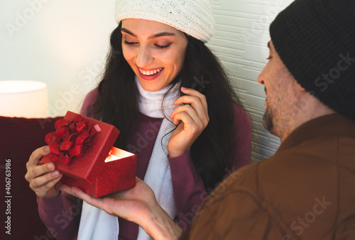 caucasian man giving gift to young girlfriend in anniversary day. They stay togerther at home. photo