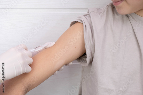 doctor in gloves preparing to vaccinate a teenager