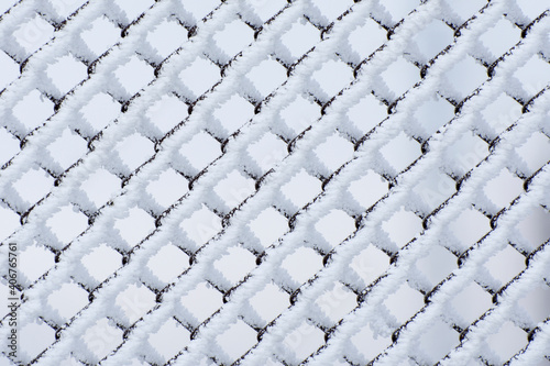 Frost-covered metal mesh. Winter background.