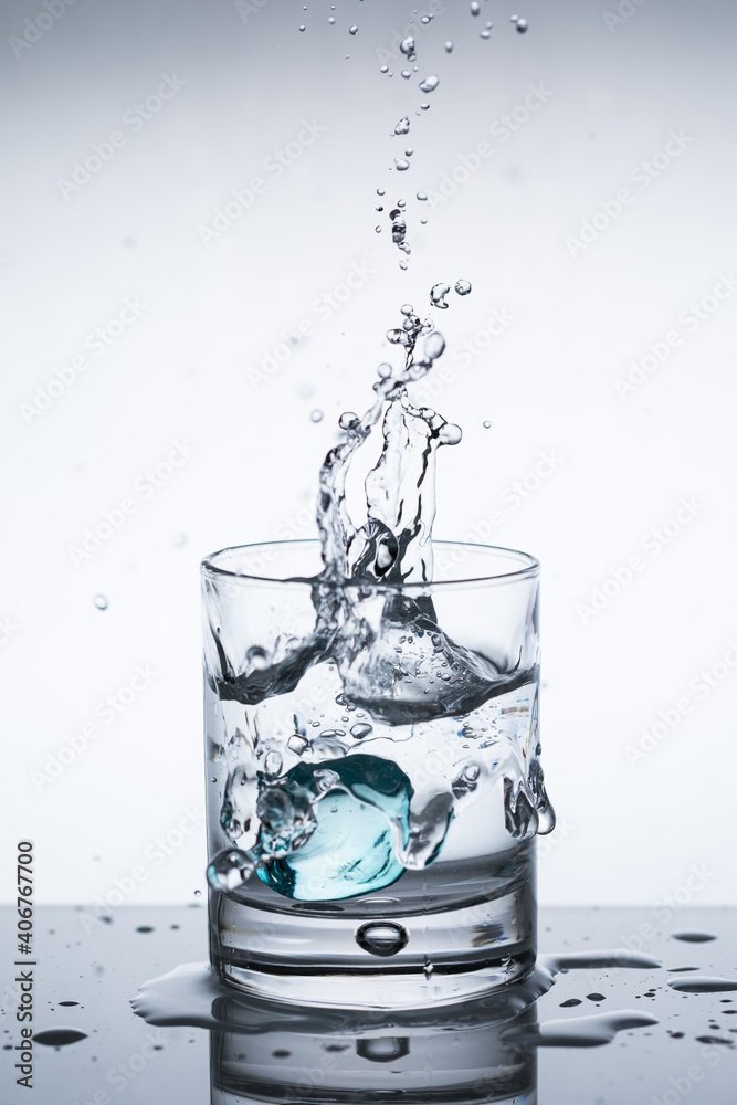 Splash of ice in a glass of water, ice falls into water, closeup Splash of ice in a glass of water, ice falls into water, closeup