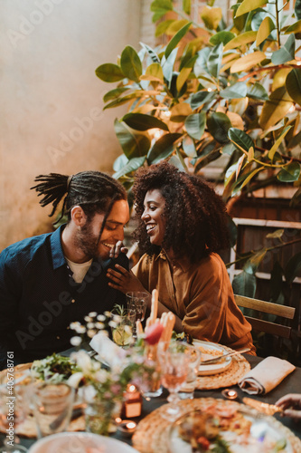 Young adult mixed race couple chatting and flirting at dinner party