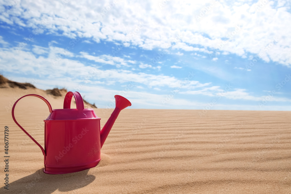 Pink watering can on sand in desert. Space for text Pink watering can on sand in desert. Space for text