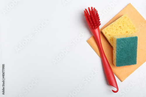 Cleaning brush, sponges and rag on white background, flat lay with space for text. Dish washing supplies