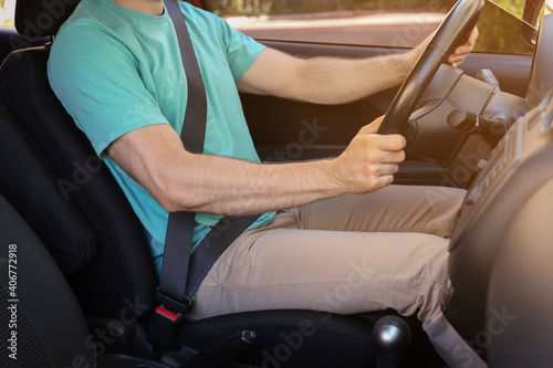 Man with fastened safety belt on driver's seat in car, closeup