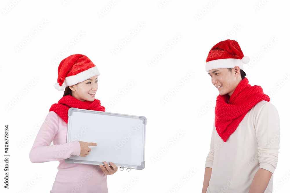 Portrait of young couple wearing Santa hats,holding whiteboard Portrait of young couple wearing Santa hats,holding whiteboard