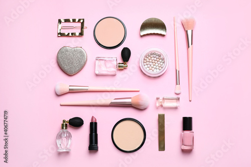 Makeup brushes and cosmetic products on pink background, flat lay