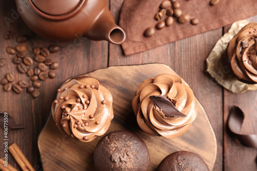 Delicious chocolate muffins and cupcakes decorated with cream on wooden table, flat lay