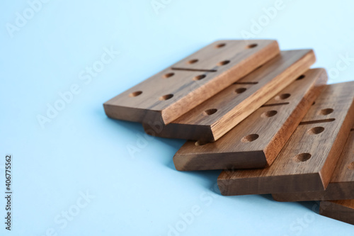 Fallen wooden domino tiles on light blue background