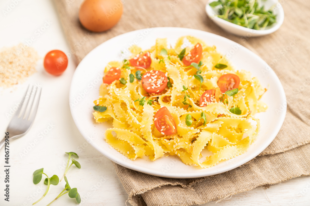 Reginelle semolina pasta with tomato, eggs, sesame and microgreen sprouts on a white wooden background. Side view, selective focus.