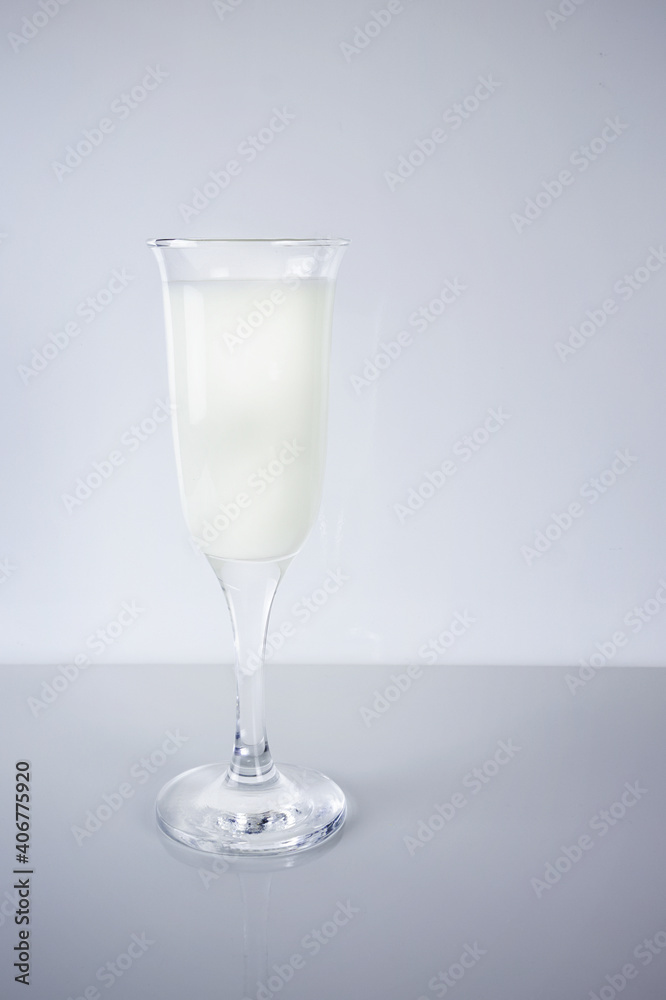 Milk in transparent wineglass on light background Milk in transparent wineglass on light background