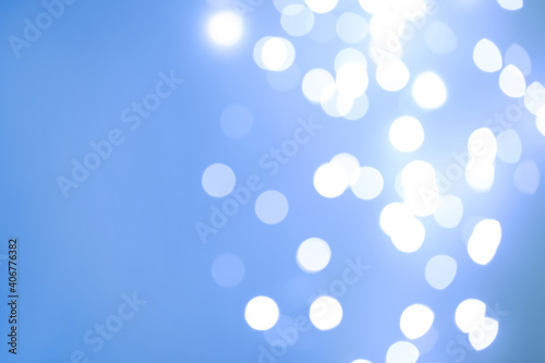Blurred view of beautiful lights on light blue background, space for text