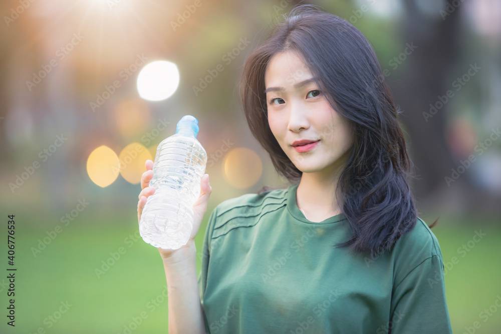Young Asian woman drinking water after work out in the park Young Asian woman drinking water after work out in the park