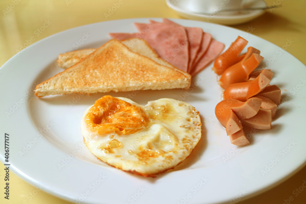 Breakfast dish of lovely heart shaped fried egg, sausages and hams with toasts