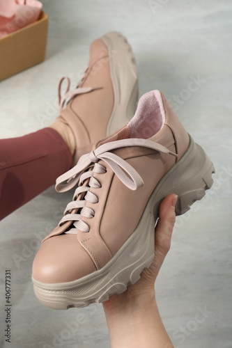 Young woman trying on shoes indoors, closeup