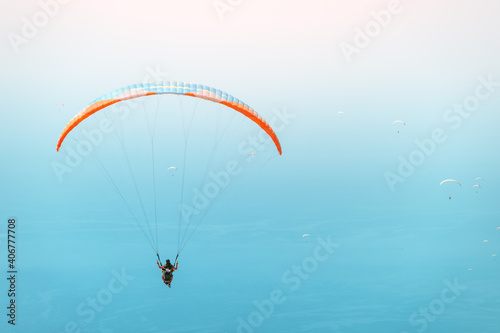 Group of paragliders flying in the blue sky. Extreme and air activity and sport concept. Blue sea at the background