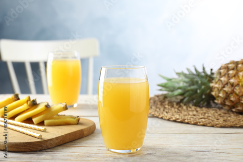 Delicious pineapple juice in glass on white wooden table