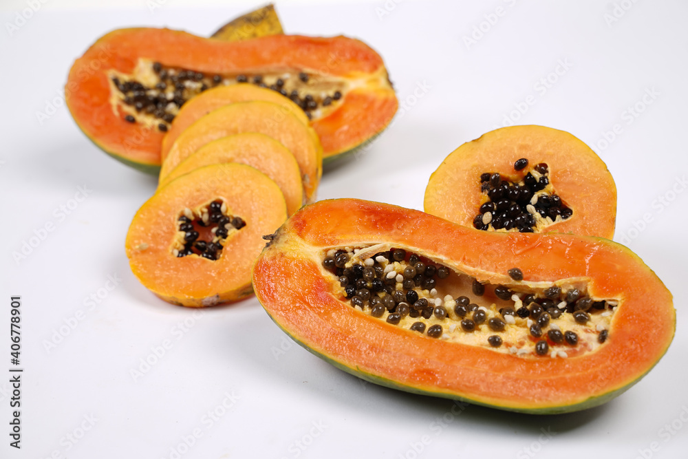 Whole Papaya fruit with a few slices isolated on a bright background. Close-up of juicy and delicious fresh papaya. Overripe papaya that starts to rot will give off a sweet, honey-like liquid.