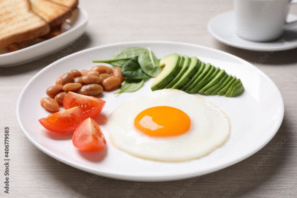 Tasty breakfast with fried egg, beans and avocado served on white wooden table, closeup Tasty breakfast with fried egg, beans and avocado served on white wooden table, closeup