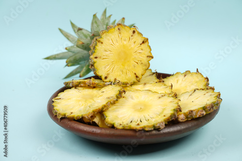 Whole pineapple with a few slices isolated on a bright background. Close-up of juicy and delicious fresh pineapples. Overripe pineapple that starts to rot will give off a sweet, honey-like liquid.