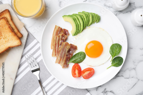 Tasty breakfast with fried egg, bacon and avocado served on white marble table, flat lay