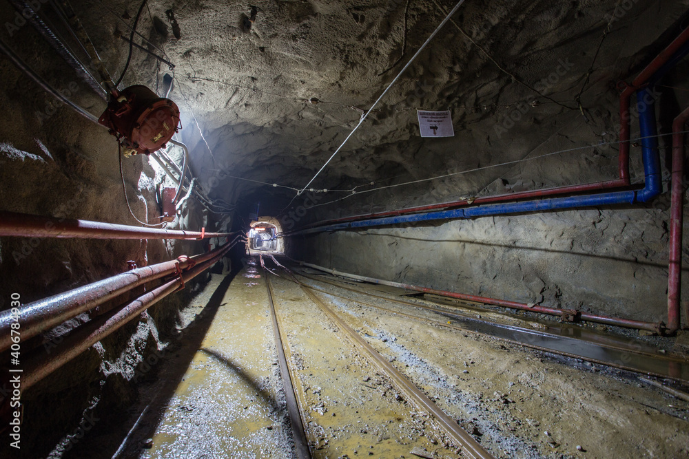 Naklejka premium Underground gold mine shaft tunnel drift with rails and light
