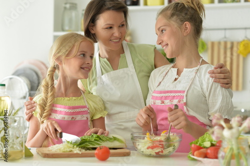 Portrait of cute girls with mother cooking in kitchen
