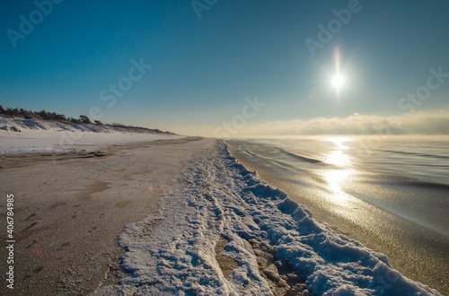 Snow Curonian Spit dunes in January winter sunny day. Blue sky and sea  no people on the beach  calm and beautiful view. Near Klaipeda city in Lithuania