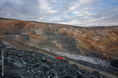 Gold mine open pit quarry with working diiger and drilling machine
