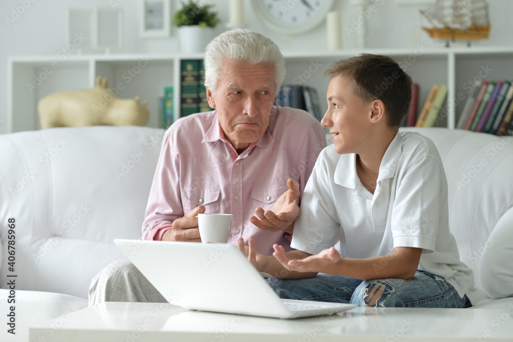 Obraz premium Boy and grandfather with a laptop at home