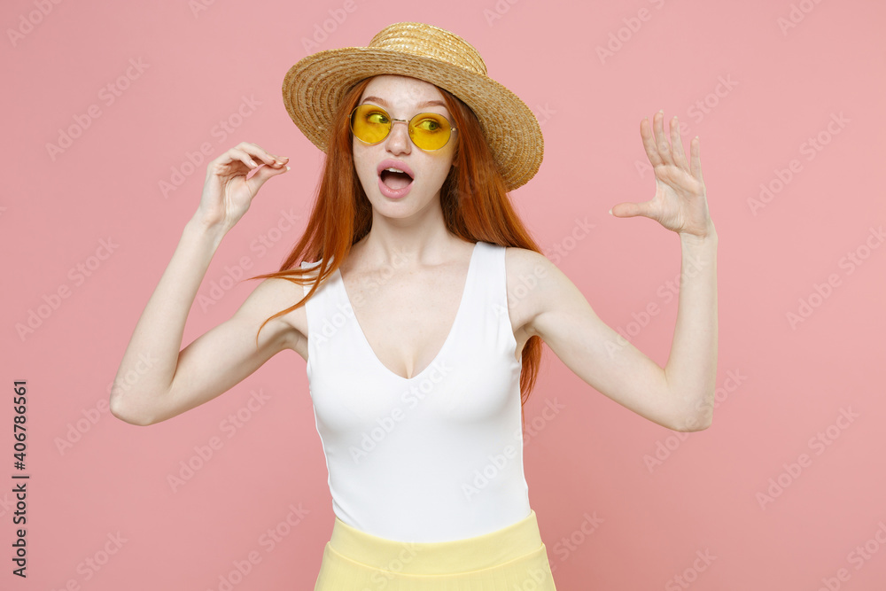 Young caucasian redhead woman 20s ginger long hair wearing straw hat glasses summer clothes show blah blah gesture ja jaja hands looking aside isolated on pastel pink color background studio portrait. Young caucasian redhead woman 20s ginger long hair wearing straw hat glasses summer clothes show blah blah gesture ja jaja hands looking aside isolated on pastel pink color background studio portrait.