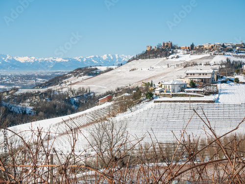 Italy Piedmont: Barolo wine yards unique landscape winter, Novello medieval village castle on hill top, the Alps snow capped mountains background, italian historical heritage grape agriculture
