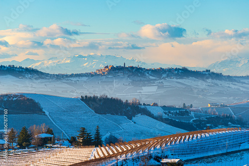 Italy Piedmont: Barolo wine yards unique landscape winter sunset, La Morra medieval village castle on hill top, the Alps snow capped mountains background, italian heritage grape agriculture
