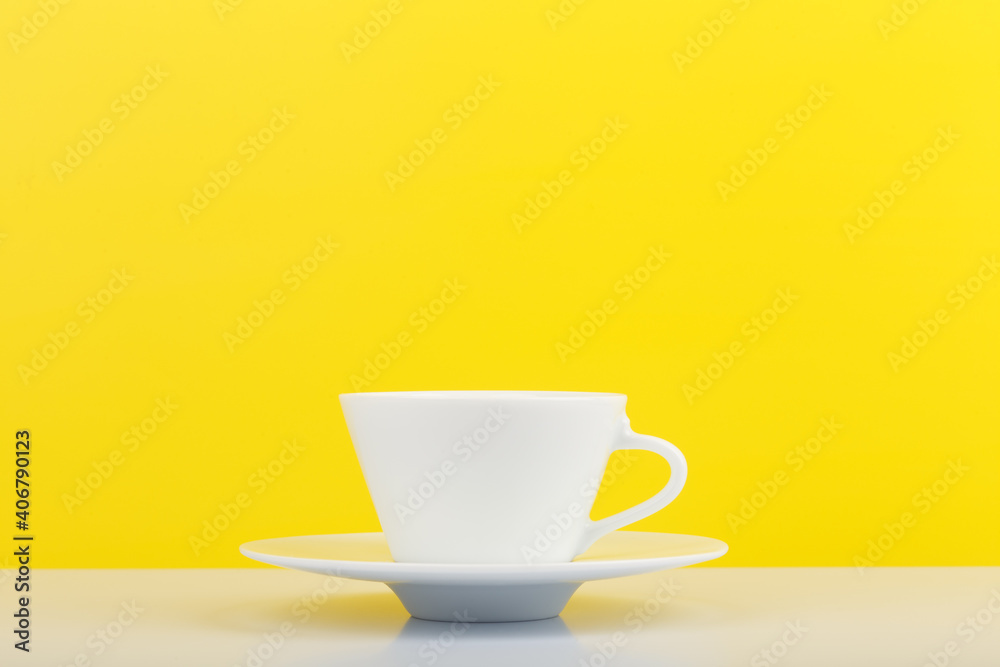 Minimalistic still life with white glossy cup of coffee on white table against yellow background with copy space. Minimalistic still life with white glossy cup of coffee on white table against yellow background with copy space.