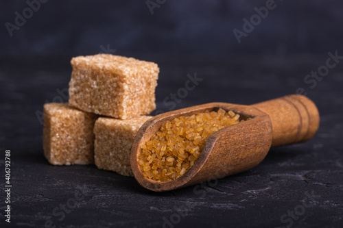 Three cubes of cane sugar and a wooden spoon with sugar sand