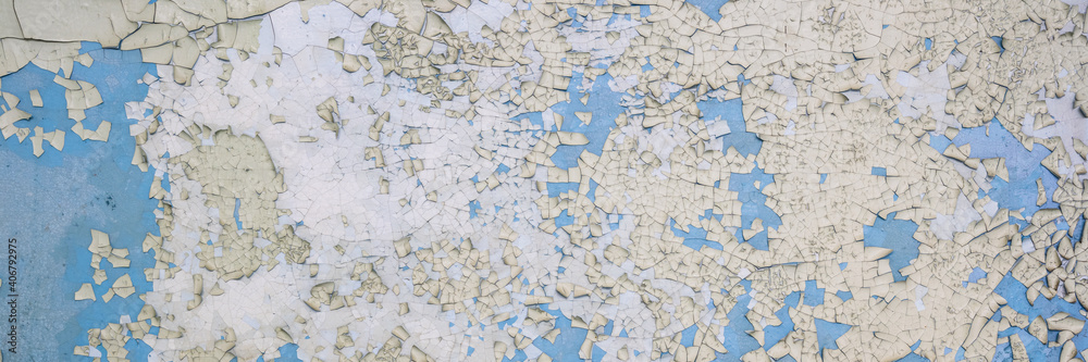 Naklejka premium Peeling paint on the wall. Panorama of a concrete wall with old cracked flaking paint. Weathered rough painted surface with patterns of cracks and peeling. Wide panoramic grunge texture for background